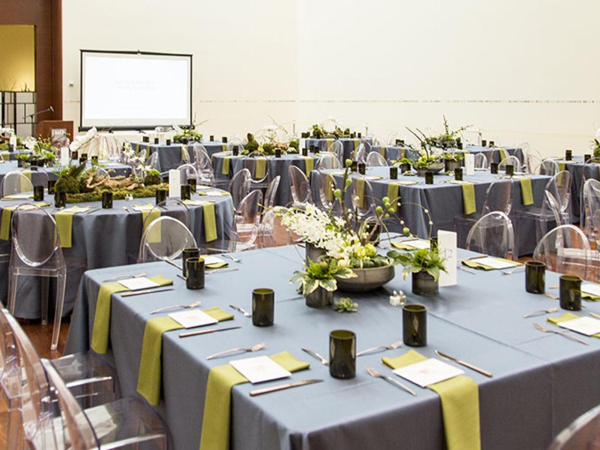 Modern wedding table settings lucite chairs with green and gray linens in the UMFA Great Hall 